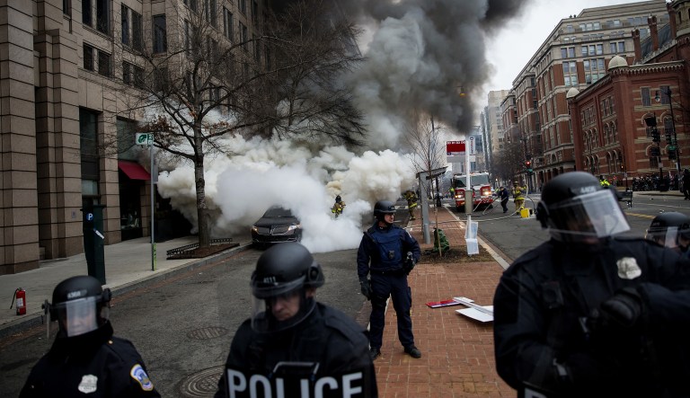 Police officers stand as smoke rises from a car set on fire during a demonstration after the 58th presidential inauguration in January. (Eric Thayer/Bloomberg)