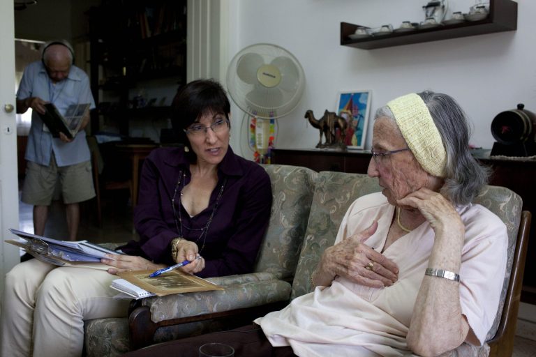 In this photo take on Sunday, May 5, 2013, Holocaust survivor Rivka Fringeru, 82, right, hold her chest as she speaks to Cynthia Wroclawski, director of Yad Vashem names collection project as they sit at her living room in Rehovot, central Israel. With a hand on her chest and moistness building in her eyes, 82-year-old Rivka Fringeru battled back tears as she reeled off a list of names she has rarely voiced in the past 70 years. First her father, Moshe, then her mother, Hava, and finally her two older brothers, Michael and Yisrael - all perished in the Holocaust after the Harabju family from Dorohoi, Romania was rounded up in 1944 and sent to ghettos and camps. Only Rivka and her brother Marco survived, and like so many others they spent the rest of their lives trying to move on and forget. Now, Yad Vashem, Israel's national Holocaust memorial and museum, is asking them to remember. (AP Photo/Ariel Schalit)
