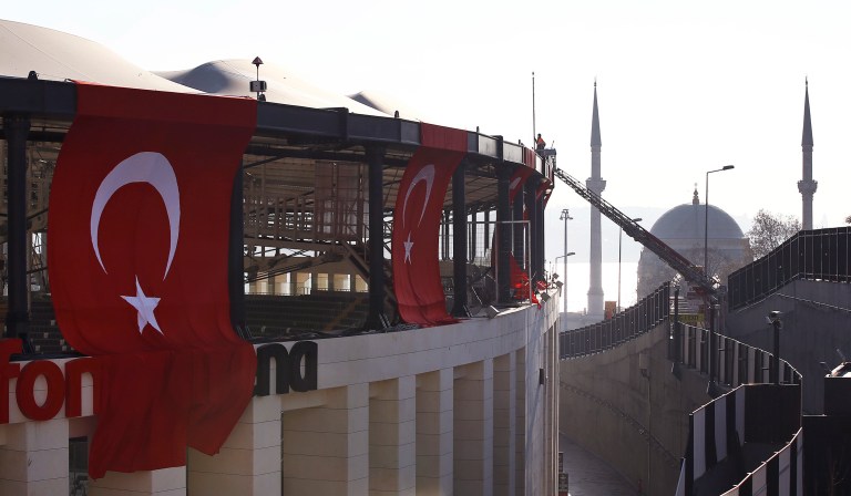 A firefighter works on the roof of the Besiktas football club stadium Vodafone Arena decorated with Turkish flags in Istanbul, Sunday, Dec. 11, 2016 following the late Saturday explosion. (AP Photo/Emrah Gurel)