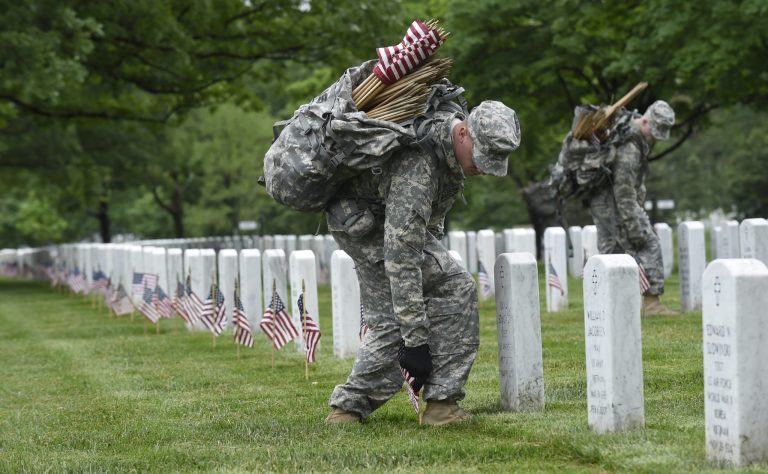 Third U.S. Infantry Regiment (The Old Guard) Pfc. Benjamin Feldbush of Stafford County, Va., places a flag in front of a headstone at Arlington National Cemetery in Arlington, Va., Thursday, May 21, 2015. 