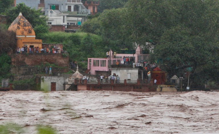 Residents watch the overflowing Chenab River after heavy rains, at Akhnoor, about 30 kilometers (19 miles) northwest of Jammu, India, Friday, Sep. 5, 2014. The region has been hit by its worst monsoon flooding in more than two decades. Power and telephone links have been cut in many areas and supplies of clean drinking water have been hit, officials said. (AP Photo/Channi Anand)