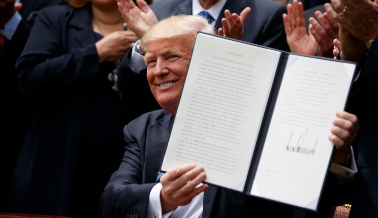 President Trump holds up a signed executive order aimed at easing an IRS rule limiting political activity for churches. (AP Photo/Evan Vucci)
