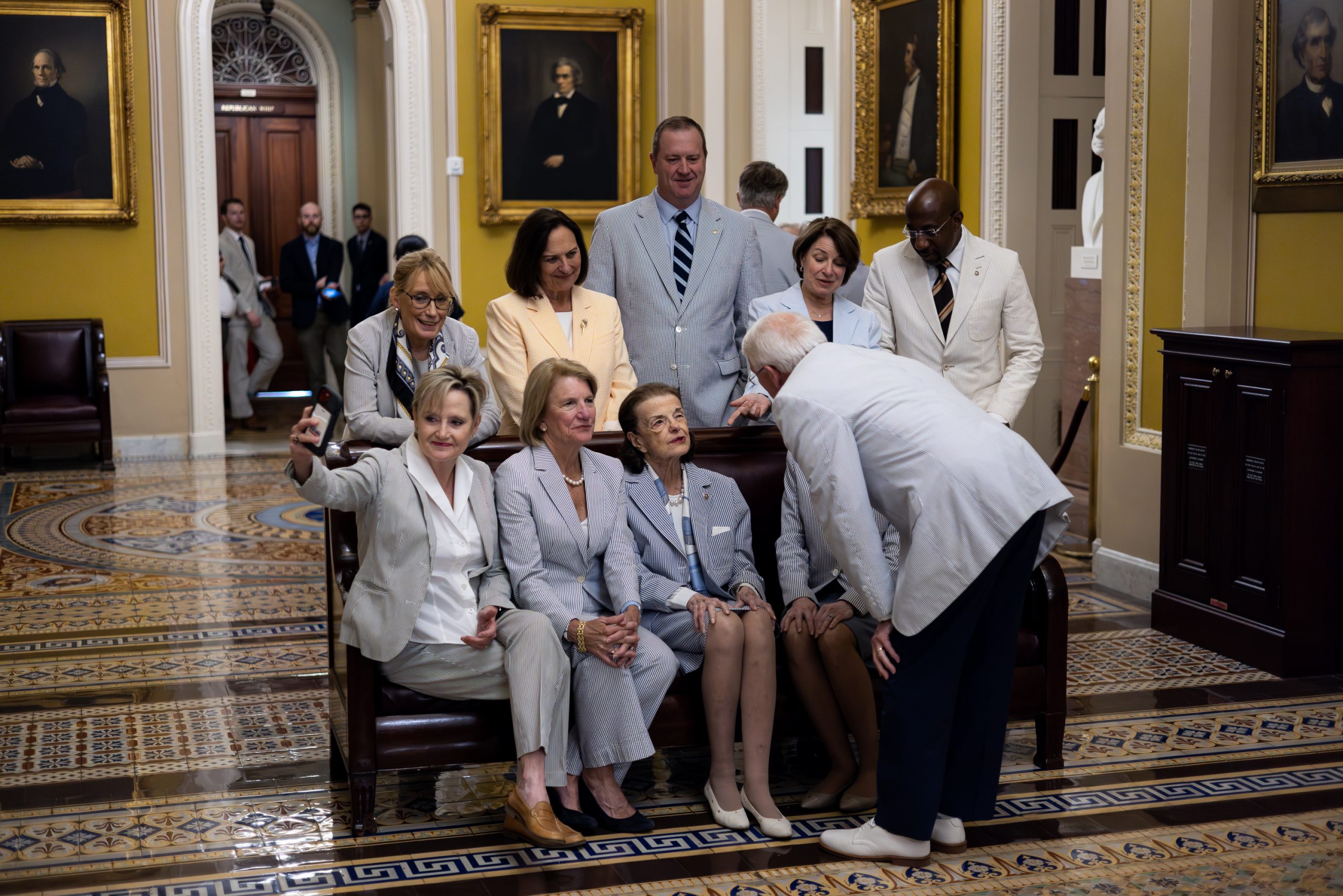 Sen. Cindy Hyde-Smith (R-MS) takes a selfie with other members of the Senate as they wait to pose for a picture to mark National Seersucker Day in the Ohio Clock Corridor of the U.S. Capitol on Thursday, June 8, 2023.