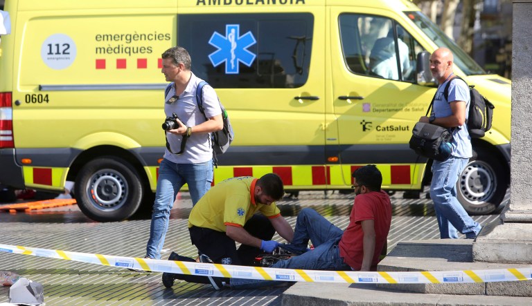 An injured person is treated in Barcelona, Spain, Thursday, Aug. 17, 2017 after a white van jumped the sidewalk in the historic Las Ramblas district, crashing into a summer crowd of residents and tourists and injuring several people, police said. (AP Photo/Oriol Duran)