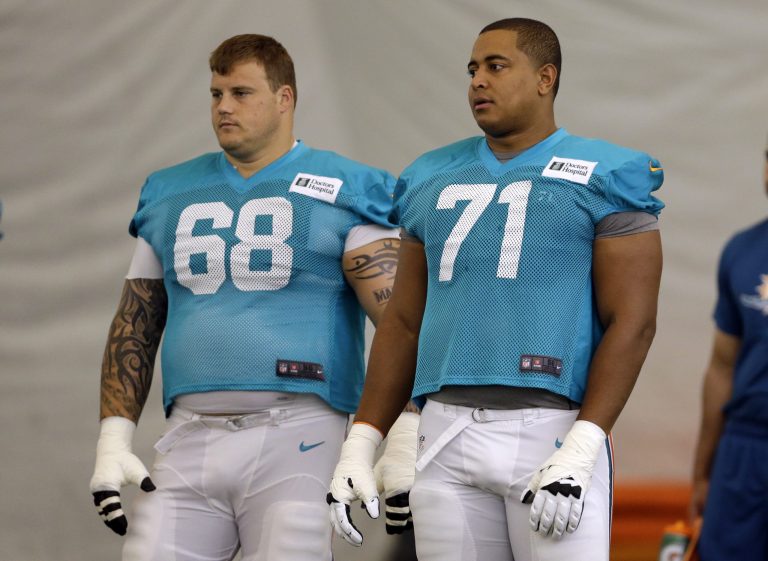 Miami Dolphins guard Richie Incognito (68) and tackle Jonathan Martin (71) stand on the field during an NFL football practice, July 2013. A new NFL investigative report found that Richie, a white, soon-to-be free agent veteran, abused Martin, a black player then in his rookie season. (AP Photo/Lynne Sladky)