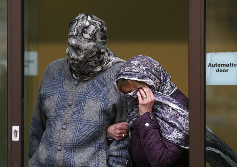 Convicted mafia boss Domenico Rancadore, left, and his wife Anne Skinner, with their faces covered leave Westminster Magistrates Court after he is granted bail while an appeal take place for his extradition to Italy, Monday, March 17, 2014. (AP Photo/Sang Tan)
