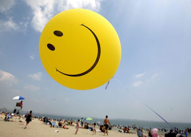 FILE - A smiley face balloon floats over Revere Beach in Revere, Mass. as beachgoers head for the water on Sunday, July 16, 2006. According to a report released in December 2013 from the National Academy of Sciences, which advises the U.S. government, by gauging happiness, there'd be more to consider than cold hard cash when deciding matters that affect daily lives. The panel of economists, psychologists and other experts assembled by the academy recommended that federal statistics and surveys, which normally deal with income, spending, health and housing, should include a few extra questions on happiness. (AP Photo/Michael Dwyer)
