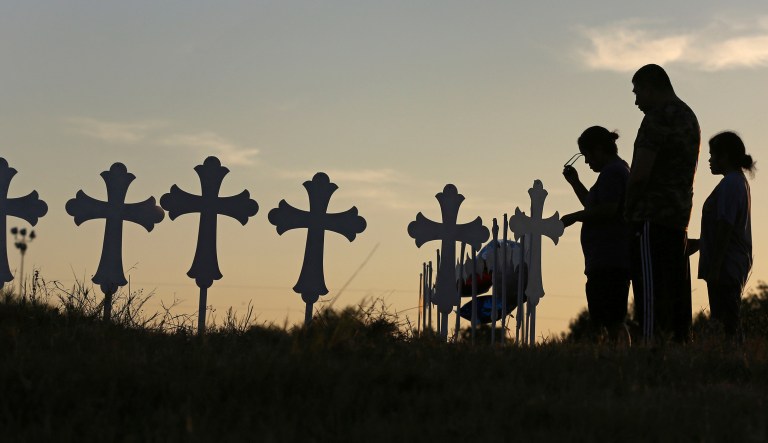 Sutherland Springs residents pray in front of some of the crosses placed in a field to honor those who were killed in Sunday's mass shooting at the town's First Baptist Church. (Louis DeLuca/The Dallas Morning News)