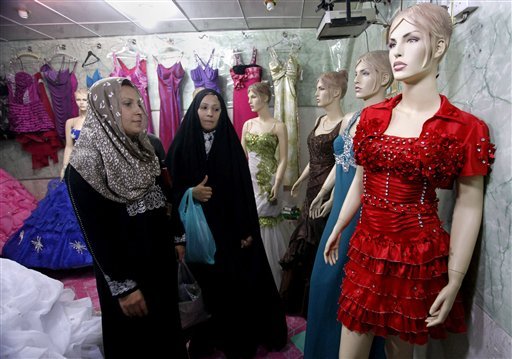 In this Sunday, Sept 2, 2012 photo, Iraqi women shop at a women's fashion store in Diwaniyah, 130 kilometers (80 miles) south of Baghdad, Iraq, Sunday, Sept 2, 2012. A new culture rift is emerging in Iraq, as young women replace shapeless cover-ups with ankle-baring skirts and tight blouses, while men strut around in revealing slacks and spiky haircuts. The relatively skimpy styles have prompted Islamic clerics in at least two Iraqi cities to mobilize the 