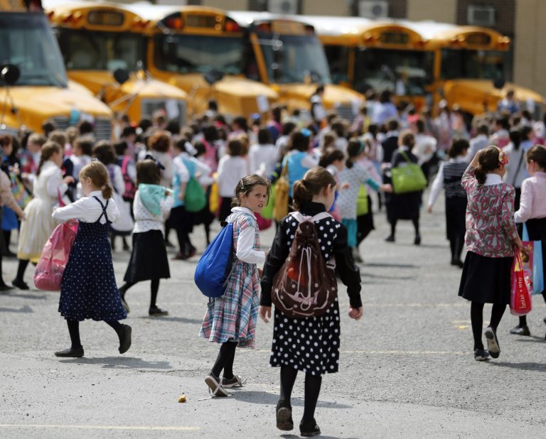 Girls walk to waiting buses after summer day camp on Tuesday, July 1, 2014, in Kiryas Joel, N.Y. Kiryas Joel is a tightly packed Hasidic enclave surrounded by suburbia in the Hudson Valley. A petition to expand the village by annexing 500 acres of leafy lots nearby has heightened tensions with some suburban neighbors. There are fears it would lead to unwanted increases in people, homes and traffic. (AP Photo/Mike Groll)