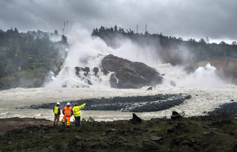 A member of Cal Fire, right, talks to workers on the Oroville Dam project in front of the main spillway in Oroville, Calif., on Feb. 20. The immense rainfall and the heavy flows of water damaged the dam's main spillway, causing a 250-foot long, 170-foot wide and 50-feet deep hole to open up in the spillway. (Hector Amezcua/The Sacramento Bee via AP, File)