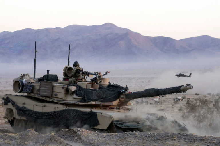 Soldiers maneuver in an M1A1 Abrams tank as an AH-64 Apache helicopter provides aerial security during exercise Decisive Action Rotation at Fort Irwin, Calif., Sept. 6, 2016. The soldiers are assigned to the 4th Infantry Divisionâs 3rd Brigade Combat Team. 