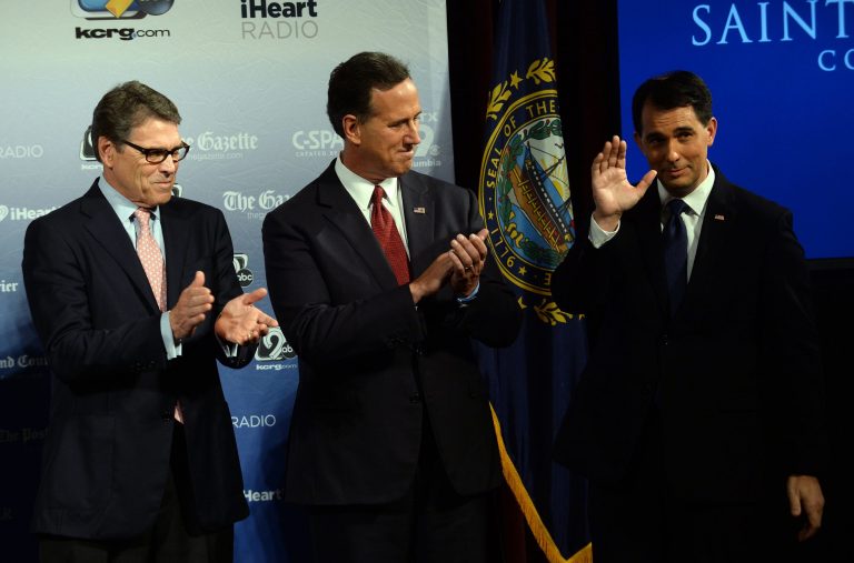 Former Texas Gov. Rick Perry (left), former Pennsylvania Sen. Rick Santorum (center) and Wisconsin Gov. Scott Walker (right) stand on the stage prior to the Voters First Presidential Forum for Republicans at Saint Anselm College August 3, 2015 in Manchester, N.H. (Photo by Darren McCollester/Getty Images)