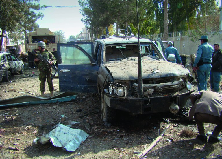 FILE - In this Jan. 26, 2012 file photo, an Afghan solider, left, stands guard at the scene of a suicide attack in Lashkar Gah, Helmand province south of Kabul, Afghanistan. Helmand was the centerpiece of President Barack Obama's surge, when he ordered 33,000 additional U.S troops to Afghanistan to help the military with a counterinsurgency plan. That plan hoped to turn the tide in Helmand and neighboring Kandahar and establish the governmental institutions that would allow the Afghan government to take control of the Taliban heartland. However, near-daily attacks by militants and increasingly frequent deadly violence against NATO troops by their Afghan allies highlight an embarrassing failure of Western policy: After nearly 12 years of military intervention, the country is not pacified. (AP Photo/Abdul Khaleq, File)
