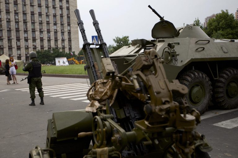 A Pro-Russian militia member guards next to an APC and anti-aircraft gun, outside the administrational building in Donetsk, Ukraine, on Thursday, May 29, 2014. Pro-Russian militia in eastern Ukraine shot down a government military helicopter Thursday amid heavy fighting around Slovyansk, killing 14 soldiers including a general. (AP Photo/Ivan Sekretarev)
