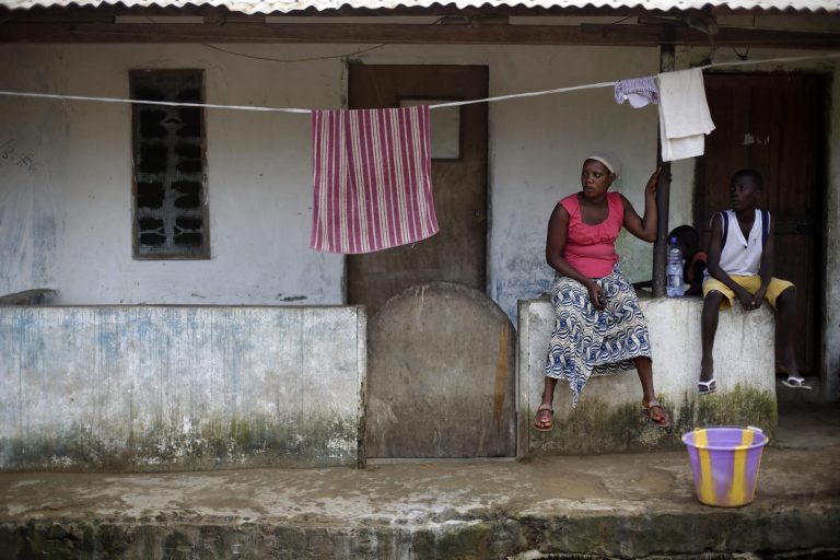 Neighbors sit in front of the house that Thomas Eric Duncan, a Liberian man now hospitalized in Texas, rented on 72nd SKD Boulevard during his stay in Liberia, in Morovia, Thursday Oct. 2, 2014. Since the announcement of his illness, Duncan has become a symbol of how Ebola could spread within the United States. Here in Liberia, though, he is just another neighbor infected by a virulent Ebola cluster ravaging this neighborhood of tin-roof homes along 72nd SKD Boulevard.(AP Photo/Jerome Delay)
