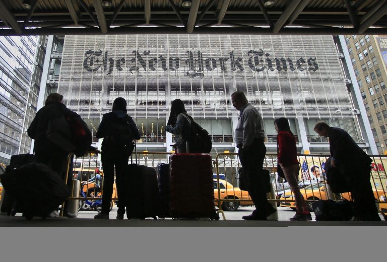 Pedestrians wait for cabs across the street from the New York Times on Wednesday in New York.