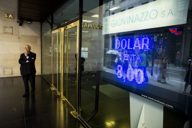 A man stands next to a sign indicating the exchange rate between the Argentine peso and the U.S. dollar in Buenos Aires, Argentina, Thursday, Jan. 23, 2014.  The peso has plunged just over 17 percent in the last two days against the U.S. dollar, and economic analysts expect inflation to hit 30 percent this year. (AP Photo/Victor R. Caivano)