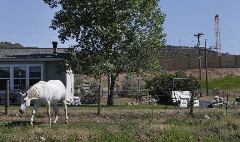 ADVANCE FOR SUNDAY, JUNE 15 AND THEREAFTER - This photo taken June 9, 2014 shows a horse named Primo grazing in front of the home of local resident Joann Aramillo, with an oil and gas rig on a well pad visible a few hundred yards away, top right, in New Castle, a small farming and ranching settlement on the Western Slope of the Rockies, in Colo. Four in 10 new oil and gas wells near national forests and fragile watersheds or otherwise identified as higher pollution risks escape federal inspection, unchecked by an agency struggling to keep pace with America's drilling boom, according to an Associated Press review that shows wide state-by-state disparities in safety checks. (AP Photo/Brennan Linsley)