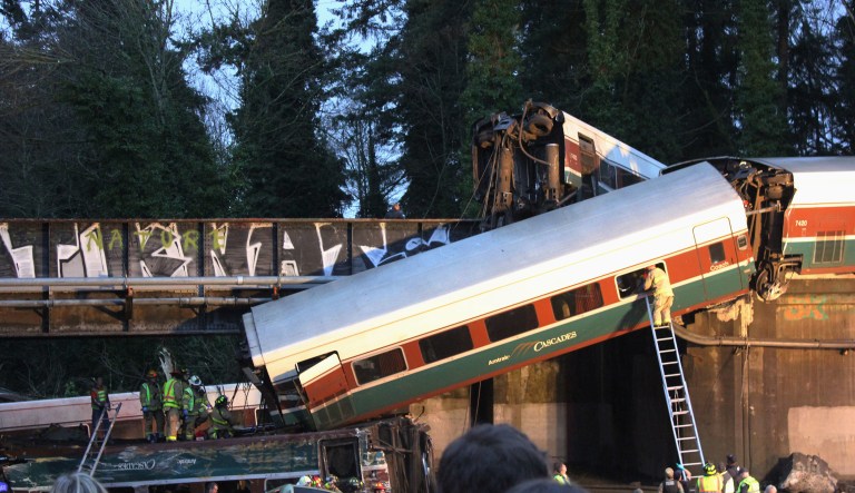 The Amtrak train making the first-ever run along a faster new route hurtled off an overpass south of Seattle and spilled some of its cars onto the highway below, killing some people, injuring dozens and crushing a few vehicles, authorities said. (Daniella Fenelon, via AP)