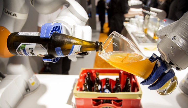 An industrial robotic arm pours a glass of beer during a trade fair in Munich, Germany.