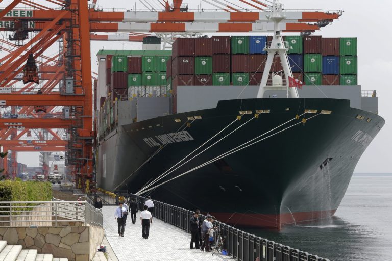 People walk in front of a container ship docked at a container terminal in Tokyo, Wednesday, April 22, 2015. (AP Photo/Shizuo Kambayashi)
