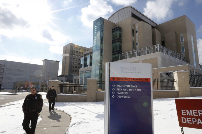 Security guards patrol the sidewalk in front of a Veterans Affairs hospital in Pittsburgh, Pa., in February 2013. (AP Photo/Keith Srakocic)