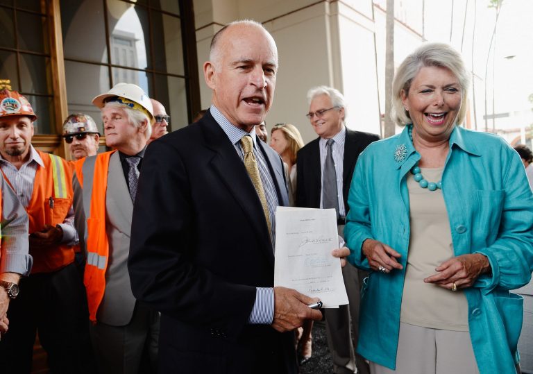 California Gov. Jerry Brown holds bill which he signed to authorize initial construction of California's $68 billion high-speed rail line with Lynn Schenk, vice chair of the Authority Board and longtime proponent of high-speed rail looking on in Los Angeles on July 18, 2012. (Kevork Djansezian/Getty Images)