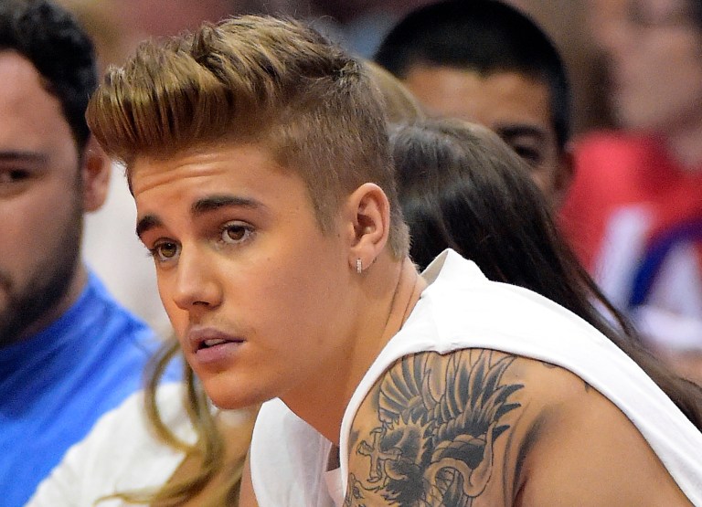 FILE - In this May 11, 2014, file photo, singer Justin Bieber watches the Los Angeles Clippers play the Oklahoma City Thunder during Game 4 of the Western Conference semifinal NBA basketball playoff series in Los Angeles. Toronto prosecutors on Monday, Sept. 8, 2014, told a court they have dropped assault charges against Bieber in connection with an incident involving a Toronto limousine driver. The charge withdrawn Monday stemmed from an early-morning incident late last December, when Bieber and five other people were picked up by a limousine from a Toronto nightclub.  (AP Photo/Mark J. Terrill, File)