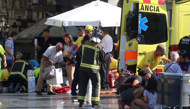 Injured people are treated in Barcelona, Spain, after a white van jumped the sidewalk in the historic Las Ramblas district, crashing into a summer crowd of residents and tourists and injuring several people, police said. (AP Photo/Oriol Duran)
