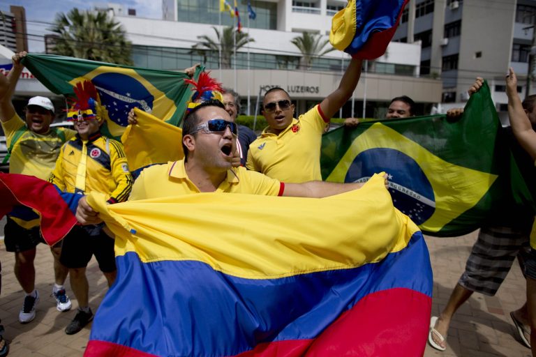 Fans of the Colombian national soccer team respond to television news cameras, waving their national flags, in front of the hotel where the Colombian national soccer team is staying in Fortaleza, Brazil, Thursday, July 3, 2014. Colombian supporters are in Fortaleza hoping to see some history being made in this northeastern World Cup city where Brazil and Colombia face off in the World Cup quarterfinals, Saturday. (AP Photo/Rodrigo Abd)