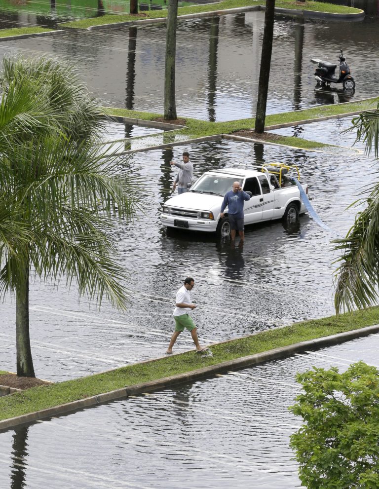 Workers pump water from the parking lot of the Dadeland Plaza shopping center Thursday after heavy rains in Pinecrest, Fla., a suburb of Miami. (AP/Wilfredo Lee)