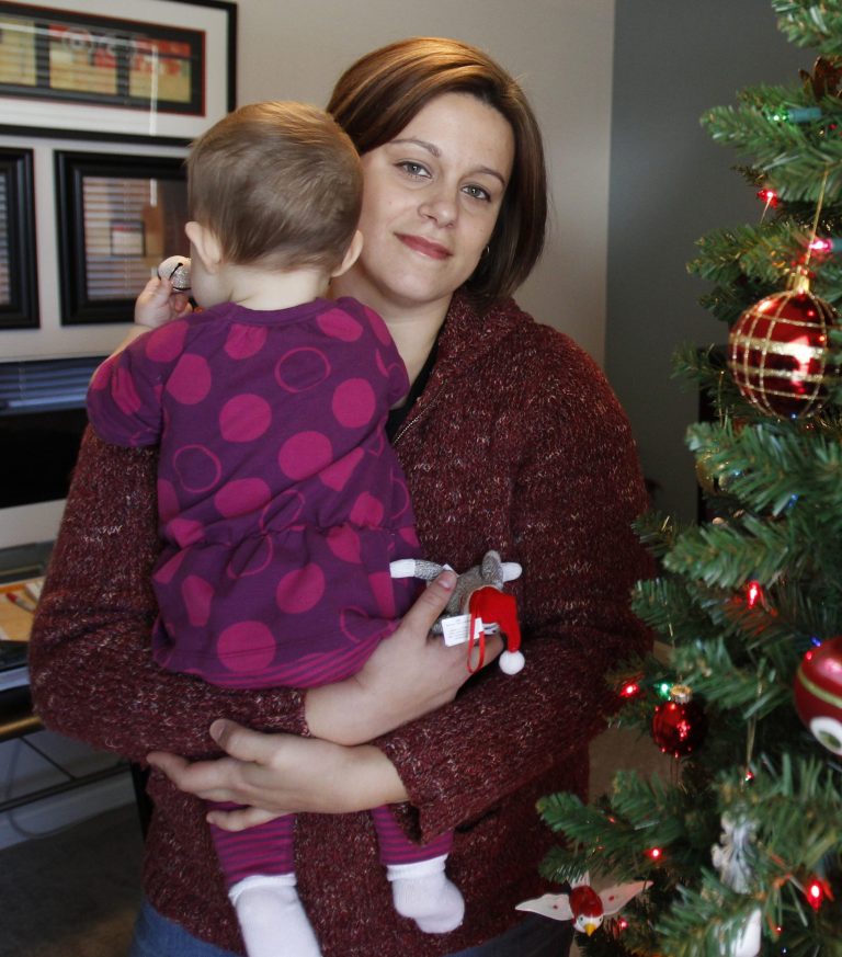 FILE - This is a Dec. 2011 file photo, Christa Dias holds her 11-month-old daughter in her Withamsville, Ohio home. Dias, a teacher who was fired from Catholic schools in 2010 after becoming pregnant through artificial insemination, testified Wednesday,May 29, 2013 in her federal lawsuit against the Roman Catholic Archdiocese of Cincinnati and two schools. She told jurors that she didn't know the procedure violated church doctrine or that she could be fired for it. (AP Photo/The Cincinnati Enquirer, Gary Landers, File) MANDATORY CREDIT; NO SALES
