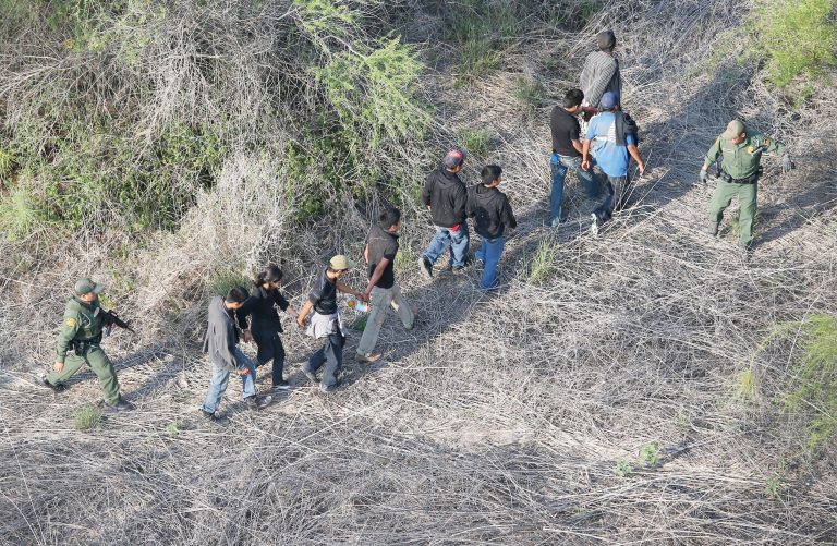 U.S. Border Patrol agents escort a group of undocumented immigrants into custody with helicopter support from the U.S. Office of Air and Marine on May 20 near the U.S.-Mexico border in Havana, Texas. The Rio Grande Valley area has become the busiest sector for illegal immigration on the whole U.S.-Mexico border with more than a 50 percent increase in the last year.  (Photo by John Moore/Getty Images)