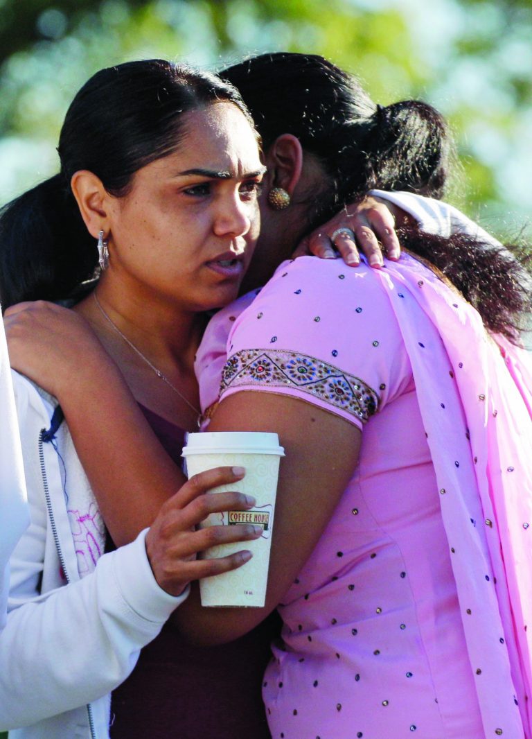 Members of the Sikh Temple of Wisconsin comfort each other Monday, Aug. 6, 2012, in Oak Creek, Wis., where a gunman killed six people a day earlier, before being shot and killed himself by police. Satwant Kaleka, 65, founder and president of the temple, died in the shooting. He was among four priests who died. (AP Photo/M. Spencer Green)