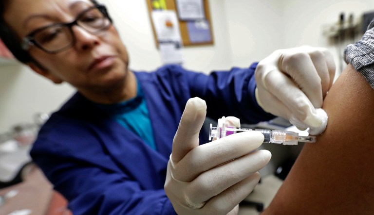 Ana Martinez, a medical assistant at the Sea Mar Community Health Center, gives a patient a flu shot, Thursday, Jan. 11, 2018 in Seattle. According to an update by the Centers for Disease Control and Prevention released Friday, Jan. 12, 2018, flu is now widespread in every state except Hawaii, but the good news is the flu season appears to be peaking. (AP Photo/Ted S. Warren)