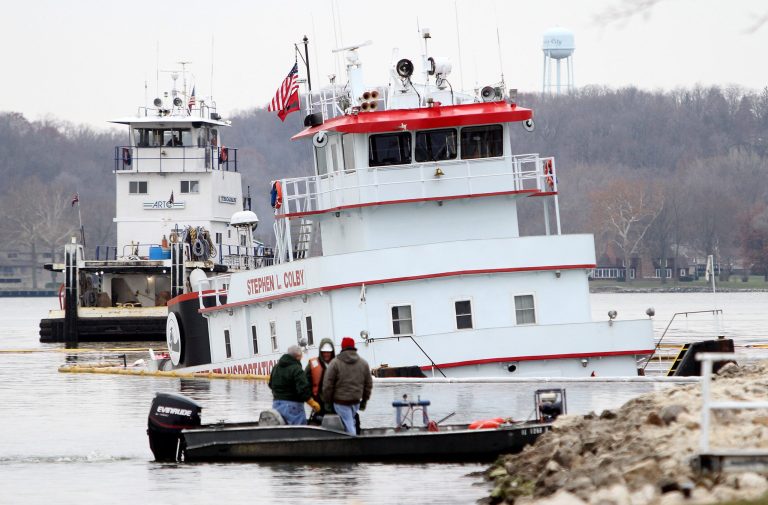 Officials inspect the towboat Stephen L. Colby Tuesday, Nov. 26, 2013 which sank Monday on the Mississippi River waterfront in LeClaire, Iowa, after striking a submerged object. Officials closed the river to barge traffic and are assessing environmental damage from the 100,000 gallons of diesel fuel and oil that leaked into the water. Nine crew members safely escaped. (AP Photo/The Quad City Times, Kevin E. Schmidt)  MANDITORY CREDIT