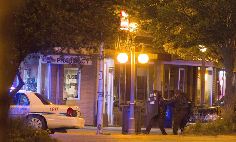   A Nebraska State Patrol SWAT team backs away from the front of Thiele Pharmacy during a 14-hour hostage-standoff Tuesday June 12, 2012 in Alliance Neb. The standoff endedwith the gunman's death. Downtown Alliance was locked down Tuesday while 27-year-old Andres Gonzales held a pharmacy owner hostage in his store. Gonzales died after a shoot-out with the Nebraska State Patrol's SWAT team. Gonzales shot one city police officer and a state patrol officer during the standoff. (AP Photo/The Omaha World-Herald, Rebecca S. Gratz) MAGS OUT. ALL NEBRASKA LOCAL BROADCAST, TV OUT.  