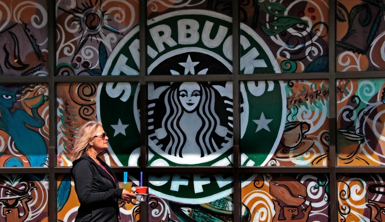 A woman walks past a Starbucks coffee shop in Sewickley, Pa., in March 2017. The coffeehouse chain expects to benefit as U.S. residents start spending some of the money they're saving on taxes, but how much is not yet clear. (AP Photo/Gene J. Puskar)