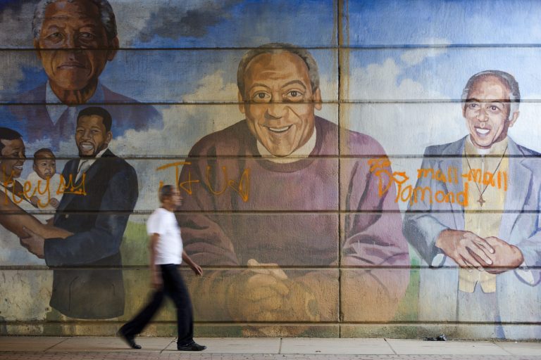 A man walks past a mural depicting entertainer Bill Cosby, center, Wednesday, July 8, 2015, in Philadelphia. (AP Photo/Matt Rourke)