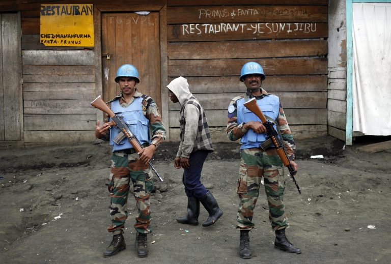 Two MONUSCO UN soldiers stand guard in Goma's port as Police Nationale du Congo officers who fled Goma when M23 rebels took over the city Nov. 18 2012, return on a barge to the port of Goma, eastern Congo, Friday Nov. 30, 2012. (AP Photo/Jerome Delay)