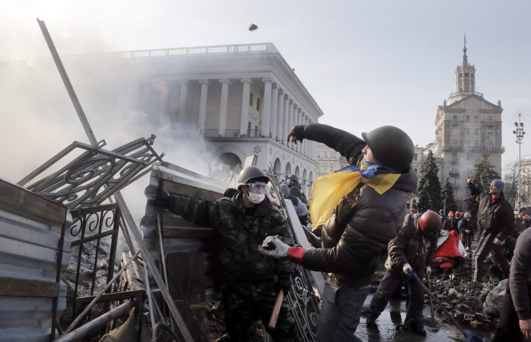 An anti-government protester throws a stone during clashes with riot police in Kiev's Independence Square, the epicenter of the country's current unrest, Kiev, Ukraine, Wednesday, Feb. 19, 2014. The deadly clashes in Ukraine's capital have drawn sharp reactions from Washington, generated talk of possible European Union sanctions and led to a Kremlin statement blaming Europe and the West. (AP Photo/Efrem Lukatsky)