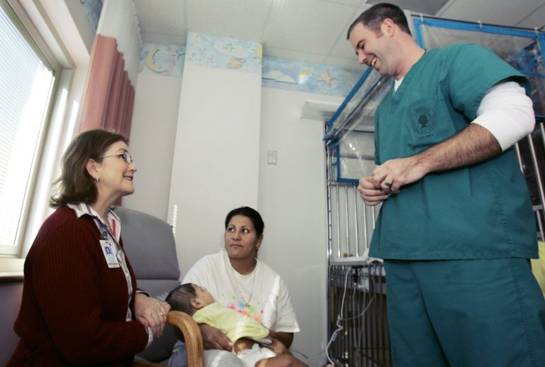 Spanish language interpreter Victoria Cochran, left, interprets between Arkansas Children's Hospital nurse Jon Emmerling, right, and Claudia Lozano, center, as she holds her eight-month-old son Arturo Cerda, a patient at the hospital, in Little Rock, Ark., Friday, Dec. 1, 2006. (AP Photo/Danny Johnston)