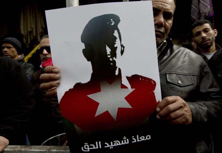 A Jordanian demonstrator carries a poster with a picture of slain Jordanian pilot, Lt. Muath al-Kaseasbeh, and Arabic that reads, 