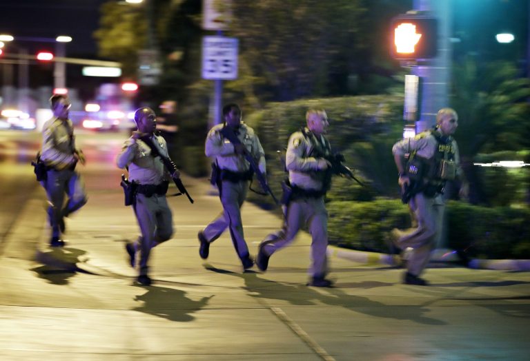 Police run at the scene of a shooting near the Mandalay Bay resort and casino on the Las Vegas Strip Sunday. Twenty people were killed and more than 100 victims were being transported to hospitals. (AP Photo/John Locher)