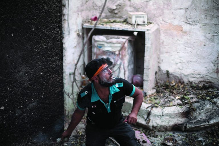 In this Wednesday, Oct. 10, 2012 photo, a Free Syrian Army fighter hurls a grenade at Syrian Army positions in the Karmal Jabl district of Aleppo, Syria. (AP Photo/ Manu Brabo)