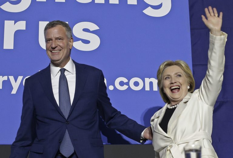 New York City Mayor Bill de Blasio, left, leads Democratic presidential candidate Hillary Clinton on stage as she waves to supporters after the CNN Democratic Presidential Primary Debate Thursday, April 14, 2016, in New York. (AP Photo/Frank Franklin II)