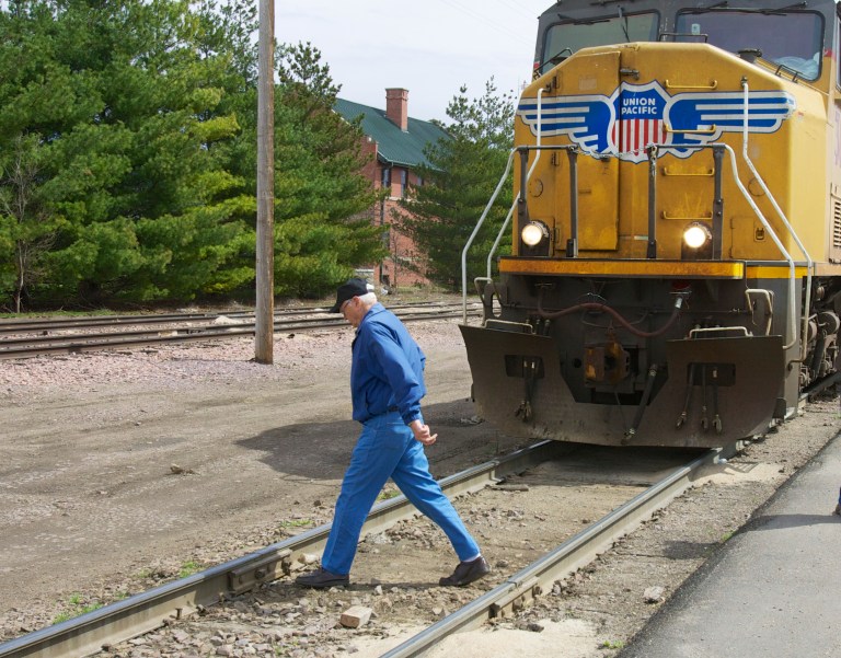 In this photo taken on April 7, 2010, a man crosses a railroad track in front of a stationary locomotive in Fremont, Neb. Regulators and the railroad industry are launching a new campaign Tuesday, April 8, 2014, to educate people about the dangers of train tracks. More people died trespassing on railroad tracks last year and more people were killed in crossing accidents. (AP Photo/Nati Harnik)