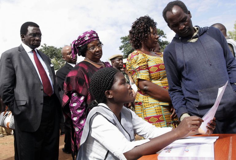 Background from left to right, Chief Justice Richard Banda, his wife, Malawi President Joyce Banda, and  younger sister  Anjimile Mtila-Oponyo, join a voting queue  to cast their votes in the eastern district of Zomba, Malawi, Tuesday, May 20, 2014. Africa's second female president Joyce Banda is facing stiff challenges from a field of 12 candidates in Malawi's elections Tuesday. (AP Photo/Raphael Tenthani)