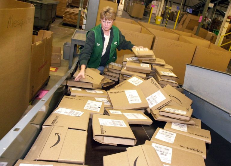 In this Nov. 13, 2002 photo, an Amazon employee sorts through orders ready to be shipped from its Coffeyville, Kan., warehouse. A Coffeyville Chamber of Commerce executive on Wednesday, Oct. 1, 2014, that the Seattle-based online retailer plans to close the facility in February, part of a move to have its distribution centers closer to the bulk of its customers. (AP Photo/The Wichita Eagle, Brian Corn)